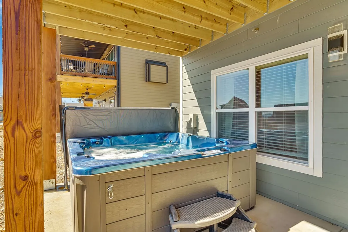 A tranquil outdoor hot tub on a deck, surrounded by wooden beams and comfortable seating. The area offers a serene setting to unwind after a day of games, with scenic views implied beyond the deck.