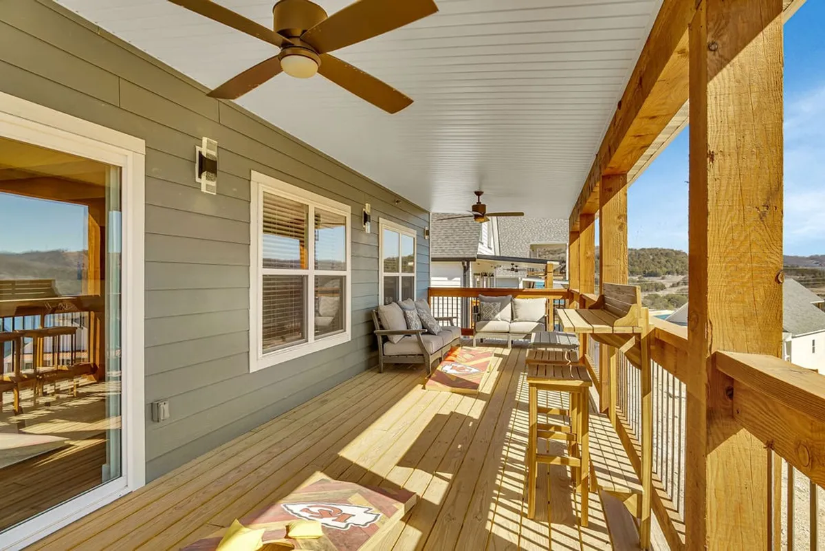 An inviting wooden deck with outdoor seating, ceiling fans, and panoramic mountain and lake views. The space is perfect for enjoying coffee at sunrise or relaxing with friends as the sun sets over the landscape.