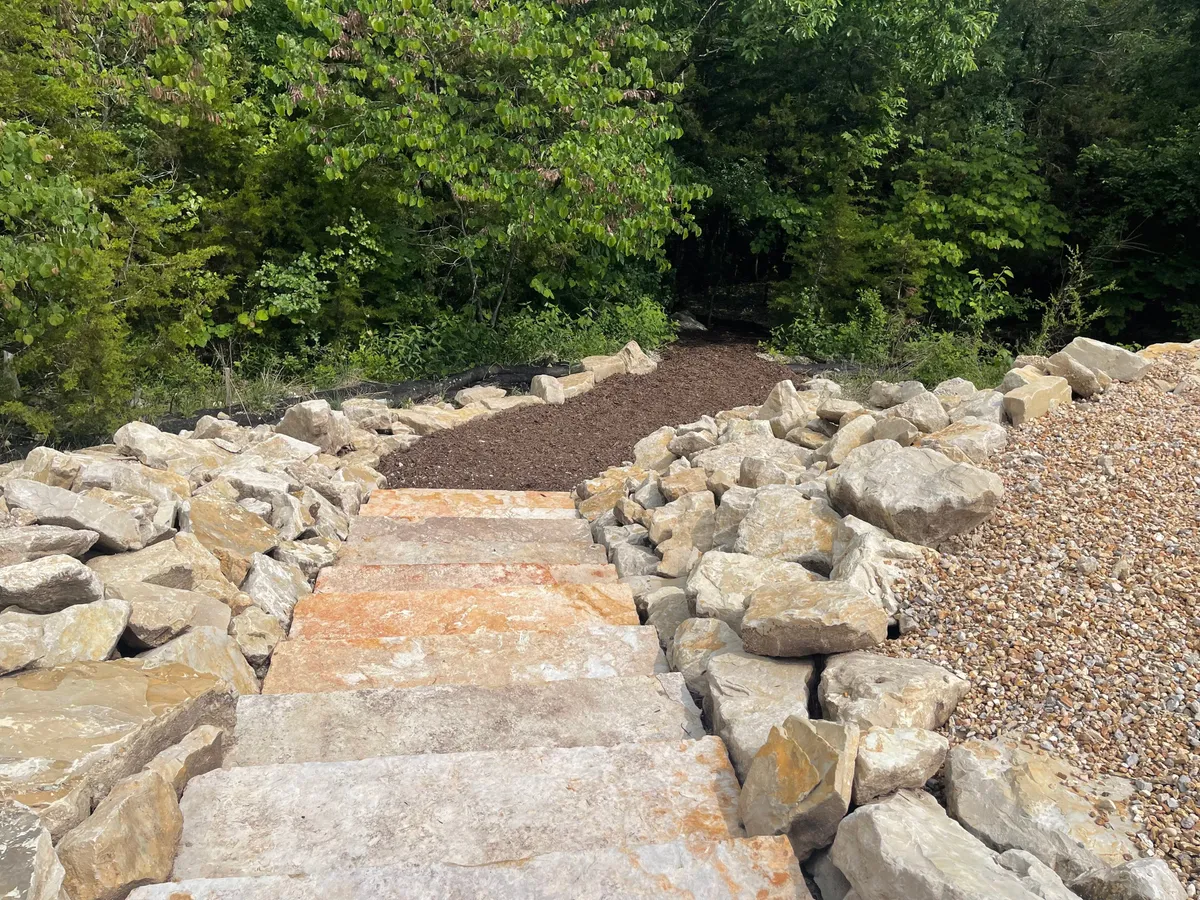 A serene outdoor trail with stone steps and lush green foliage, inviting guests to explore nature through hiking or peaceful walks during the mild spring and fall seasons.
